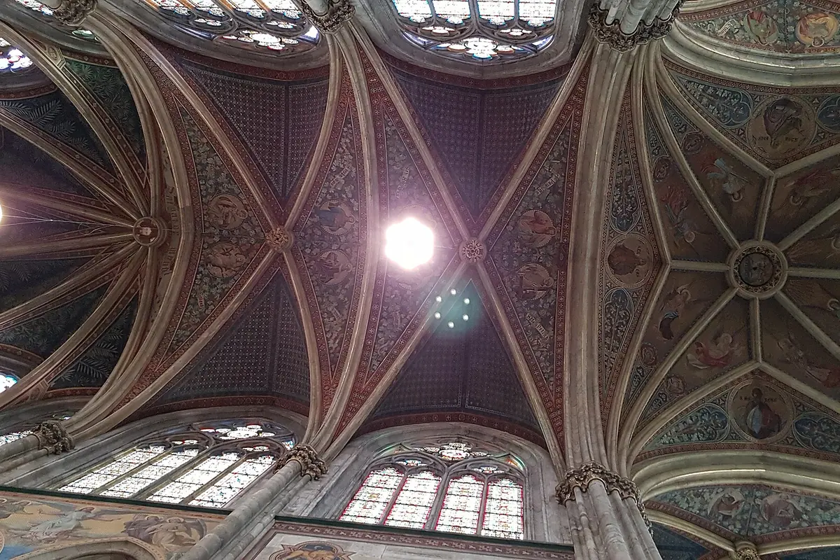 The painted star vault above the chancel of the Votivkirche, with red, blue and gold ribs radiating from a central light.